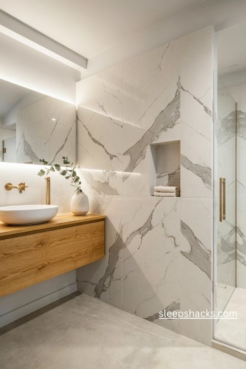 Grey veined marble bathroom with a warm oak vanity and brushed gold fixtures 