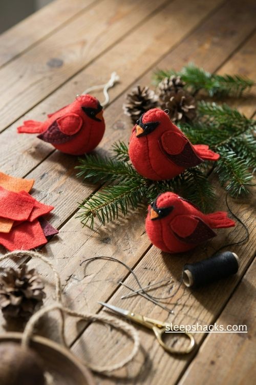 Handmade felt cardinal christmas ornaments with bright red bodies black face masks and tiny orange beaks