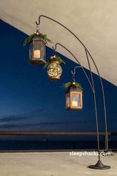 Hanging Christmas lantern cluster on a small apartment balcony with glowing battery candles evergreen sprigs and warm rustic metal details