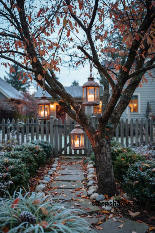 Hanging Christmas lanterns at varying heights from a tree in a rustic winter garden