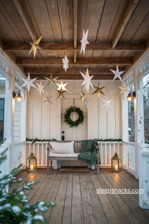 Hanging white and gold christmas stars at different heights on a cozy covered porch