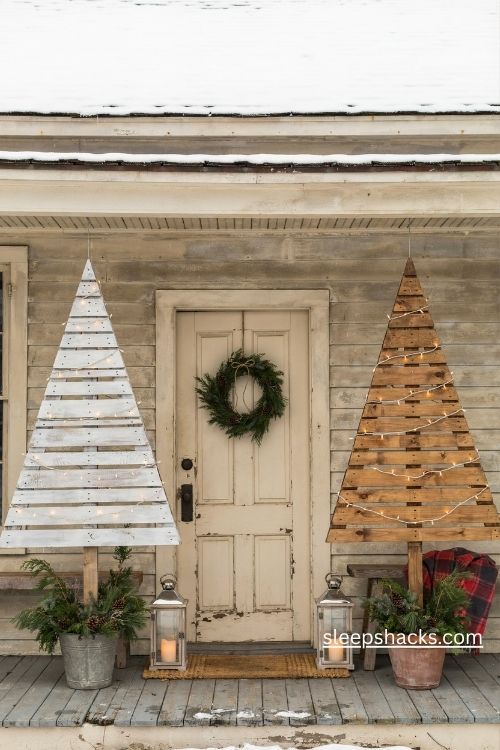 Matching pallet wood christmas trees in white and natural brown framing a rustic farmhouse front door 