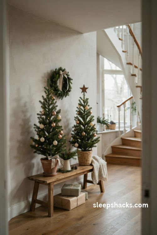 Mini Christmas trees with warm lights and simple ornaments on a farmhouse staircase landing beside wrapped gifts and a rustic wooden bench