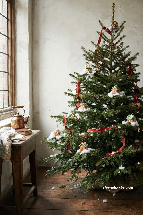 Mini gingerbread house ornaments on a Christmas tree in a cozy storybook cottage