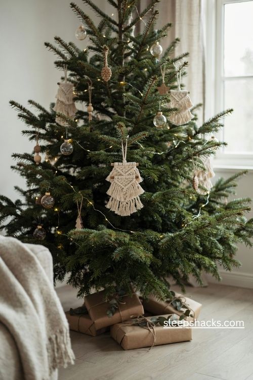 Mini macrame christmas tree ornaments in natural cream cotton cord hanging on a real evergreen tree