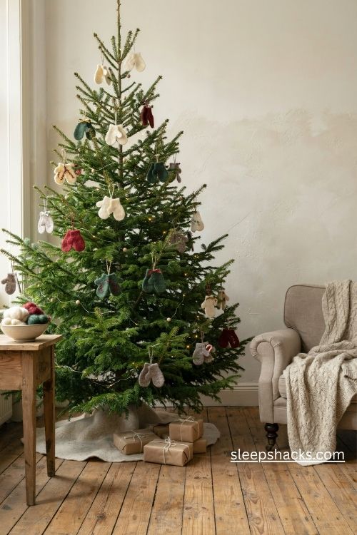 Mini wool mitten christmas ornaments with contrasting blanket stitches and tiny ribbon loops on a cozy evergreen tree