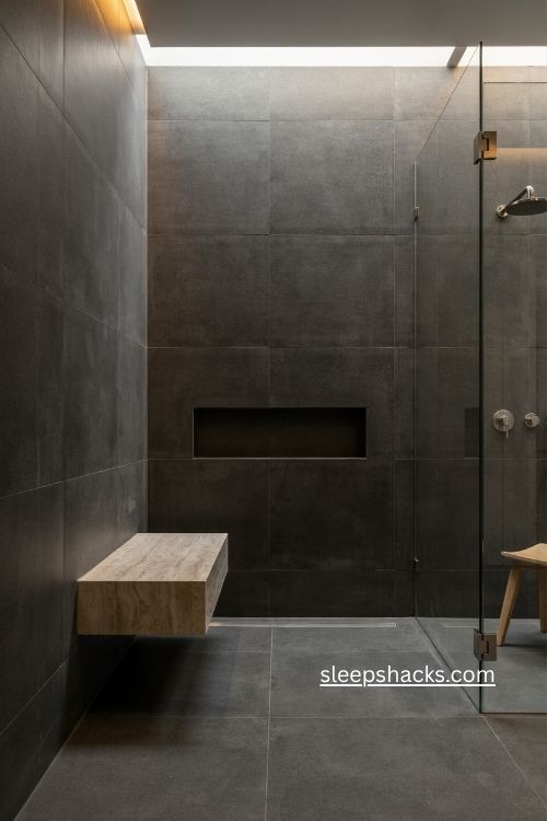 Moody minimalist bathroom with dark tile marble bench and warm lighting