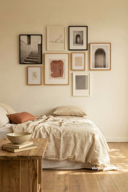 Neutral gallery wall above bed with black and white prints in a cream bedroom