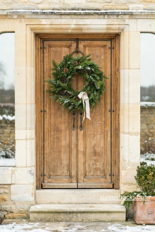 Oversized evergreen Christmas wreath on a rustic wooden front door for a bold festive entrance