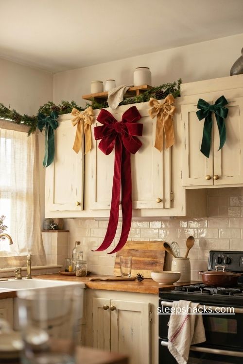 Oversized velvet christmas bows in deep red and forest green decorating farmhouse kitchen cabinet tops