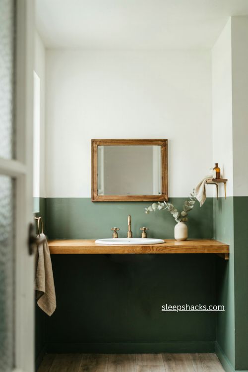 Painted split wall green bathroom with wood countertop and framed mirror