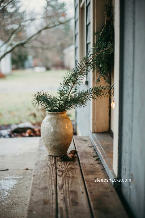 Pine branches in a stoneware jug for cozy christmas porch decor