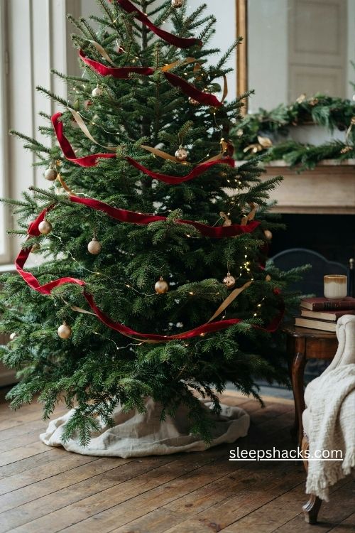 Red and gold christmas tree with deep red velvet ribbon and warm white lights