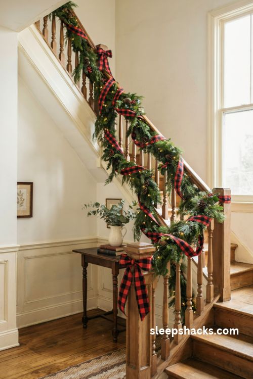 Red buffalo check plaid ribbon woven through a fresh Christmas staircase garland with farmhouse bows