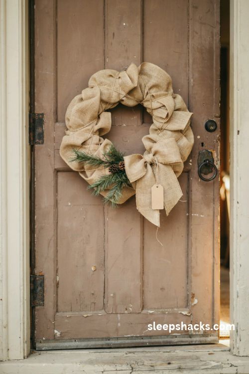 Rustic burlap and twine christmas wreath with natural fabric bow on a weathered farmhouse door