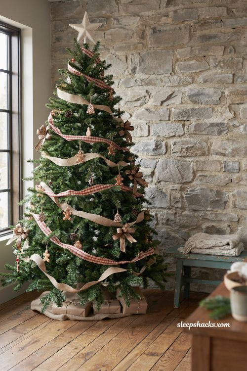 Rustic gingerbread christmas tree decorated with plaid and burlap ribbon in a cozy farmhouse living room