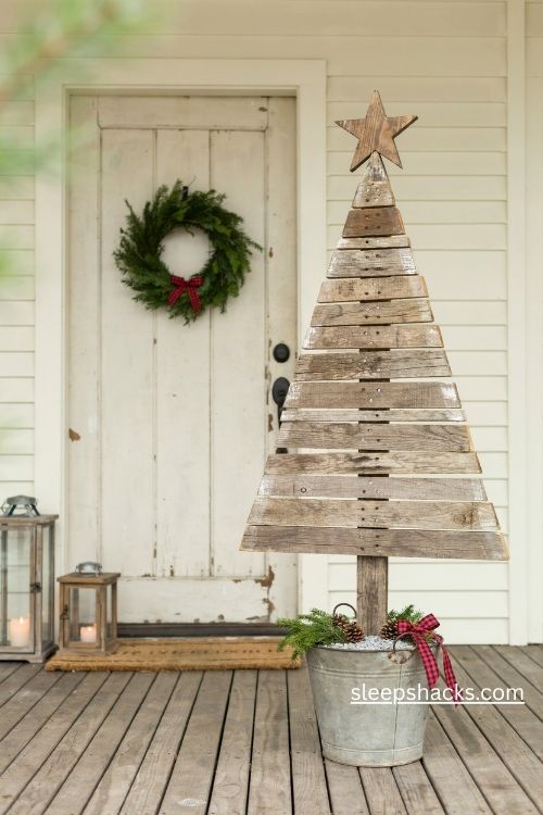 Rustic pallet wood christmas tree in a galvanized bucket with buffalo check ribbon and farmhouse porch decor 
