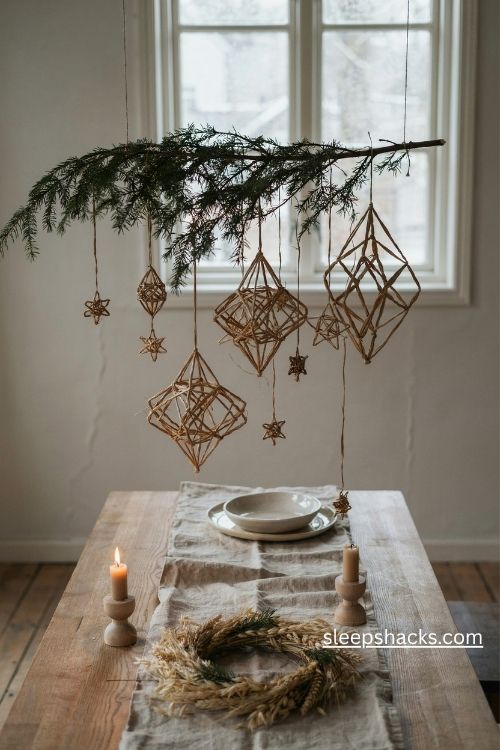 Scandi christmas straw himmeli ornaments hanging from an evergreen branch above a natural wood dining table