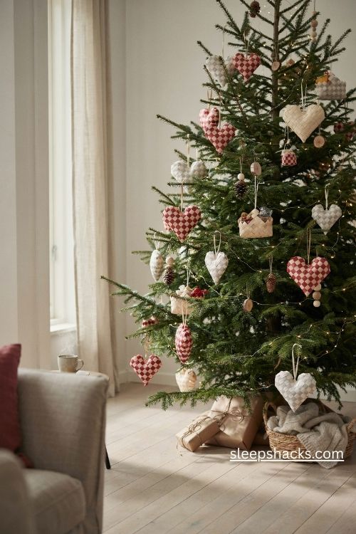 Scandi christmas woven paper heart baskets in red and cream hanging on a natural evergreen tree