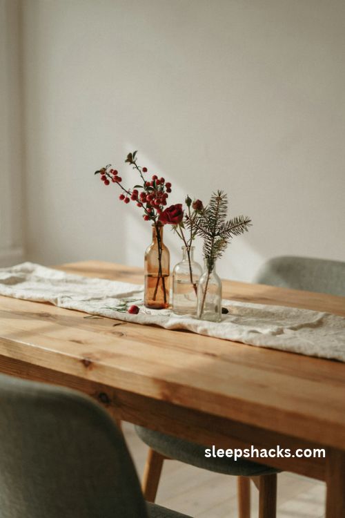 Small Christmas centerpiece with three vintage bud vases roses red berries and pine sprigs