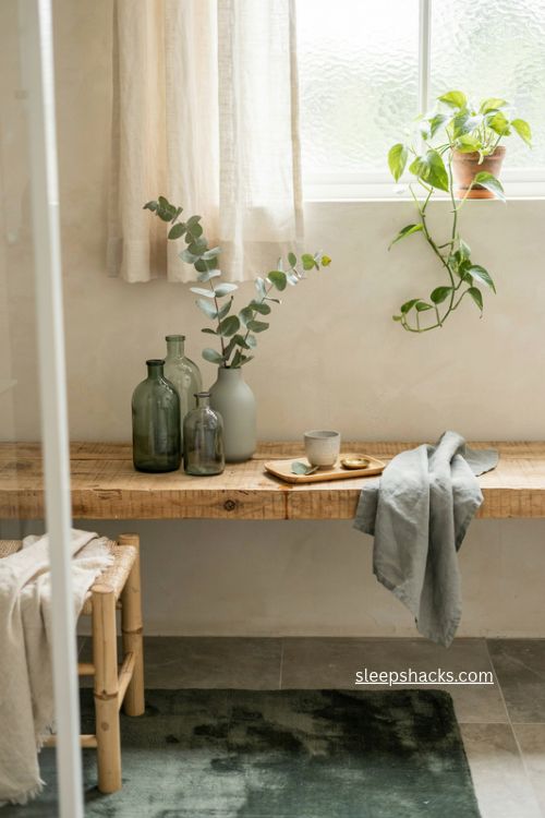Small green bathroom accents with vintage glass bottles sage towels bamboo and plants
