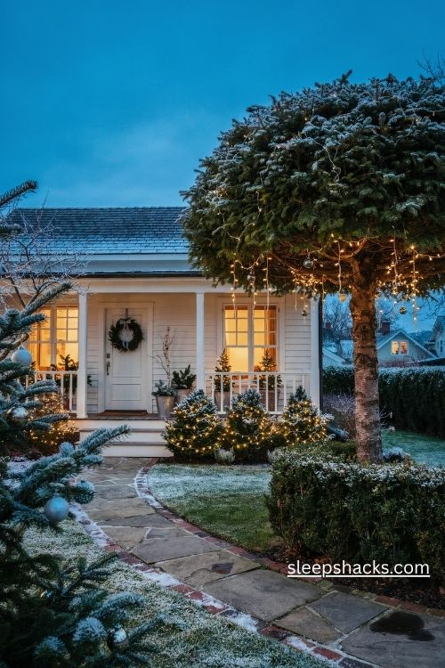 Snowy evergreen christmas front yard with warm white icicle lights frosted shrubs and silver ornaments