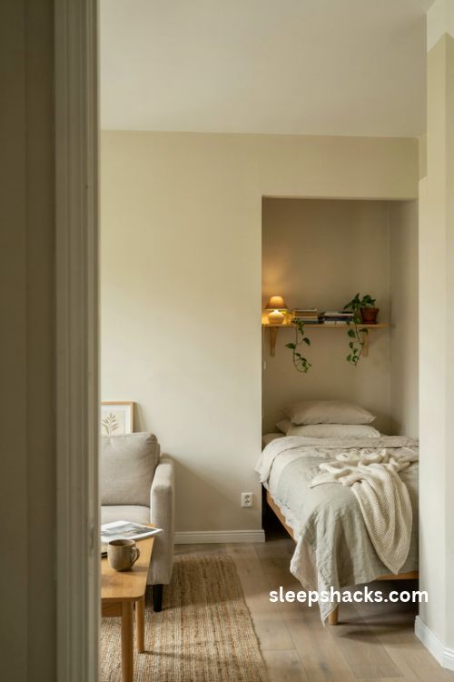 Studio apartment bed tucked into a cozy sage green corner nook with floating shelves