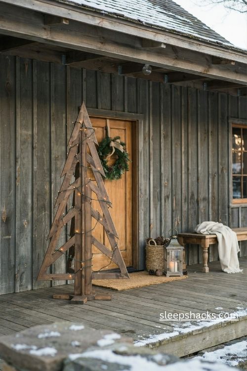 Sturdy wooden christmas tree with warm lights on a rustic farmhouse front porch 