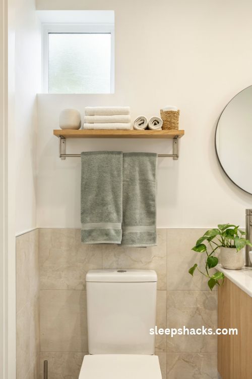 Towel rack above the toilet with a wooden shelf folded towels and stainless steel bar