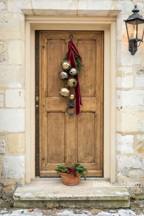 Vintage brass jingle bells hanging from a red velvet ribbon on a rustic Christmas front door