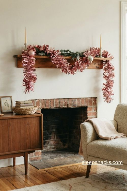 Vintage pink tinsel garland draped across a cozy mid century Christmas mantel