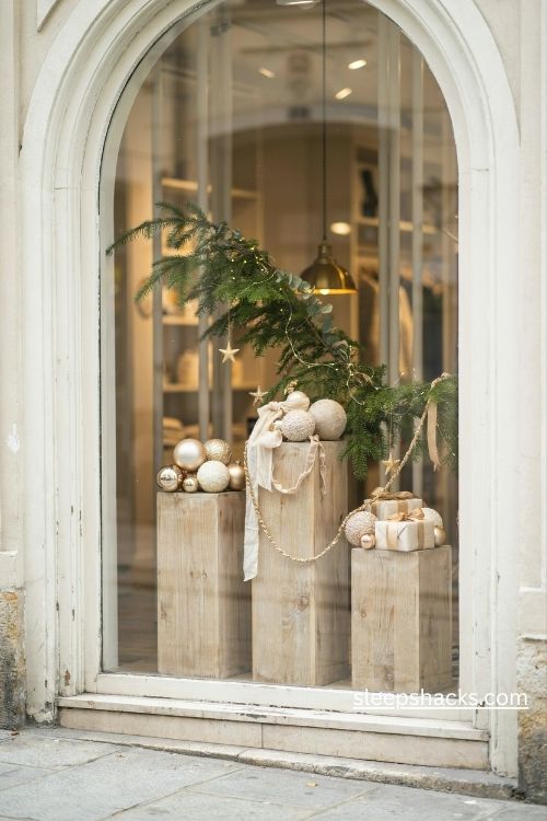 White and gold christmas storefront display with velvet ribbons matte ornaments and natural evergreen branches