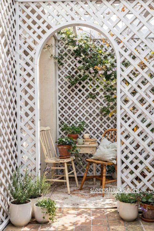 White wood lattice enclosed patio ideas with climbing plants and thrifted chairs