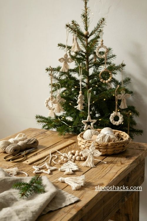 Wide close-up editorial interior photograph of a cozy Christmas crafting table beside a softly illuminated evergreen tree, capturing the simple joy of making miniature macrame Christmas trees by hand. A rustic farmhouse craft corner with a weathered wooden tabletop, a small Christmas tree in an aged galvanized metal planter, and a bright winter window that makes the handmade decorations feel inviting and achievable. Warm bohemian farmhouse style with Scandinavian cottage influences and a nostalgic handmade Christmas aesthetic. A natural palette of creamy ivory, soft oatmeal, muted sage green, deep evergreen, warm honey-colored wood, and subtle antique metal tones. Several miniature macrame Christmas tree ornaments made from chunky 3 mm cotton cord, each shaped into a neat triangular silhouette with fluffy brushed fringe resembling snow-covered fir branches, small natural wooden bead stars at the tops, and simple cotton hanging loops. Display the finished ornaments hanging naturally from evergreen branches alongside a few delicate macrame stars, while additional miniature trees rest on the wooden table beside a wooden dowel, a small unfinished cone, neatly coiled cream and sage cotton cord, vintage craft scissors, a fine-toothed pet comb, loose wooden beads, and a folded natural linen cloth. Include tiny uneven fringe strands and visible cotton fibers that celebrate the authentic beauty of beginner-friendly handmade crafts. Keep the arrangement abundant but believable, as though several ornaments have been made during a peaceful evening of holiday crafting, with plenty of open tabletop visible. Soft winter daylight streams through the window and falls gently across the rough wood grain, revealing every knot, twisted fiber, and brushed cotton fringe, complemented by the delicate warm glow of tiny Christmas tree lights. The mood is comforting, creative, nostalgic, and quietly satisfying, showing how inexpensive materials and a few simple knots can become treasured Christmas decorations. Soft cream and sage colors create instant calm, tactile cotton and weathered wood add warmth and depth, and charming handmade imperfections give the scene lasting character. Compose the scene as a Pinterest-worthy seasonal DIY photograph with clearly defined details throughout, realistic natural proportions, balanced visual richness, and a warm lived-in atmosphere that inspires viewers to try making their own ornaments. no people, no text, no watermarks, no blur, no bokeh, all surfaces in sharp focus, photorealistic, 4K resolution, editorial interior photography, Pinterest-worthy