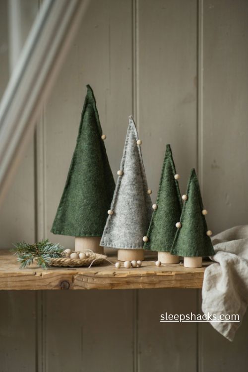Wool christmas tree decorations with handmade green felt cone trees and tiny wooden bead ornaments on a rustic shelf