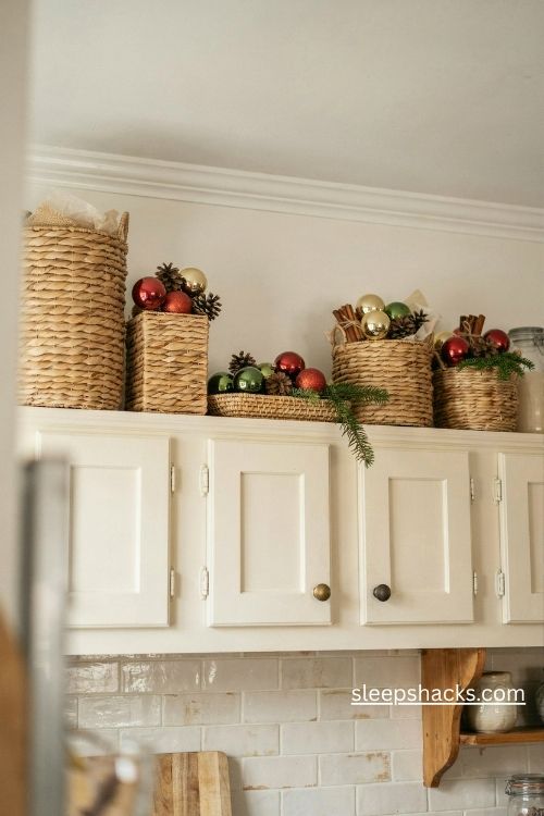 Woven christmas baskets filled with glass ornaments pinecones and cinnamon sticks above kitchen cabinets