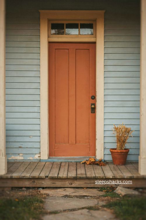 fall door decor with warm burnt orange front door and white farmhouse exterior 