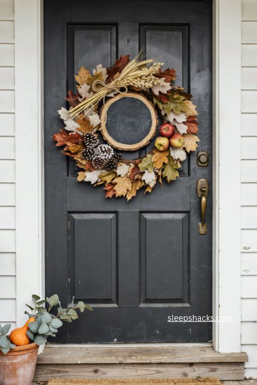 handmade fall wreath with wood slice chalkboard accent on black front door 