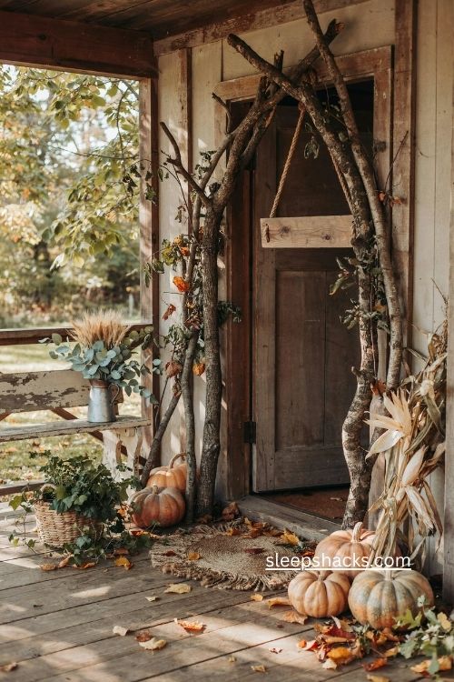 rustic fall porch door framed with branches pumpkins old bench and natural decor 