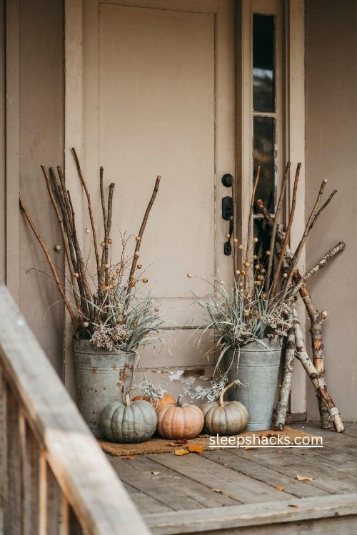 rustic fall porch planters with dried twigs grasses and small pumpkins 