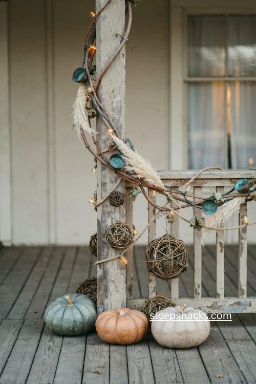 rustic fall porch with grapevine garland copper molds broomcorn and warm lights 